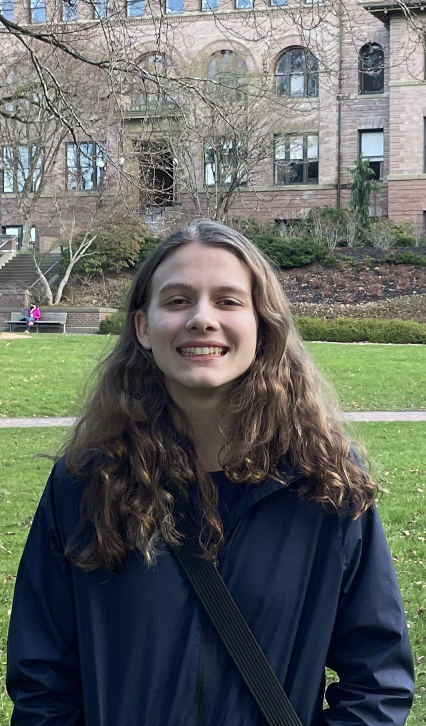 McKenna smiling in front of red brick building on WWU campus