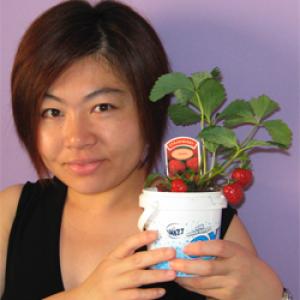 Michi smiling holding plant, in front of purple background